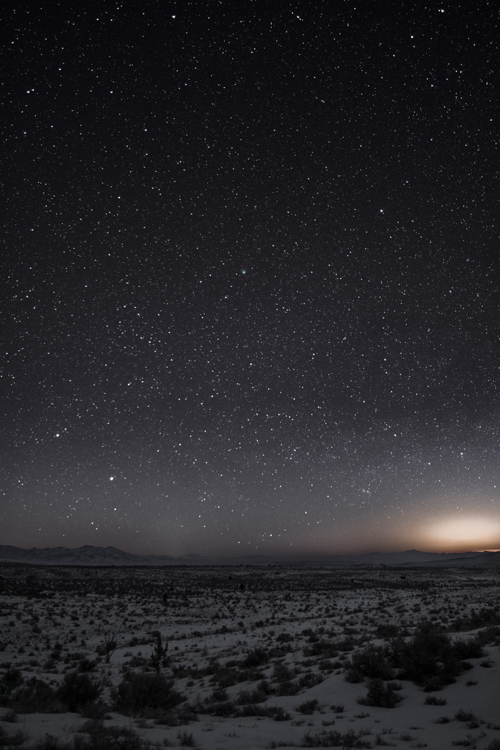 Comet E3 is visible as a hazy green dot among stars over the snowy brushland